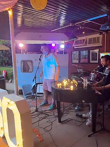 De band speelt op een verjaardagsfeest naast verlichte 60-letters