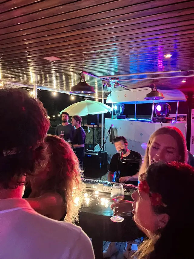 Gasten aan een tafel met lichtjes terwijl de band op de achtergrond speelt