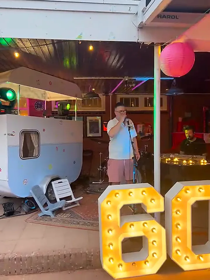Een gast zingt met de microfoon naast verlichte 60-letters